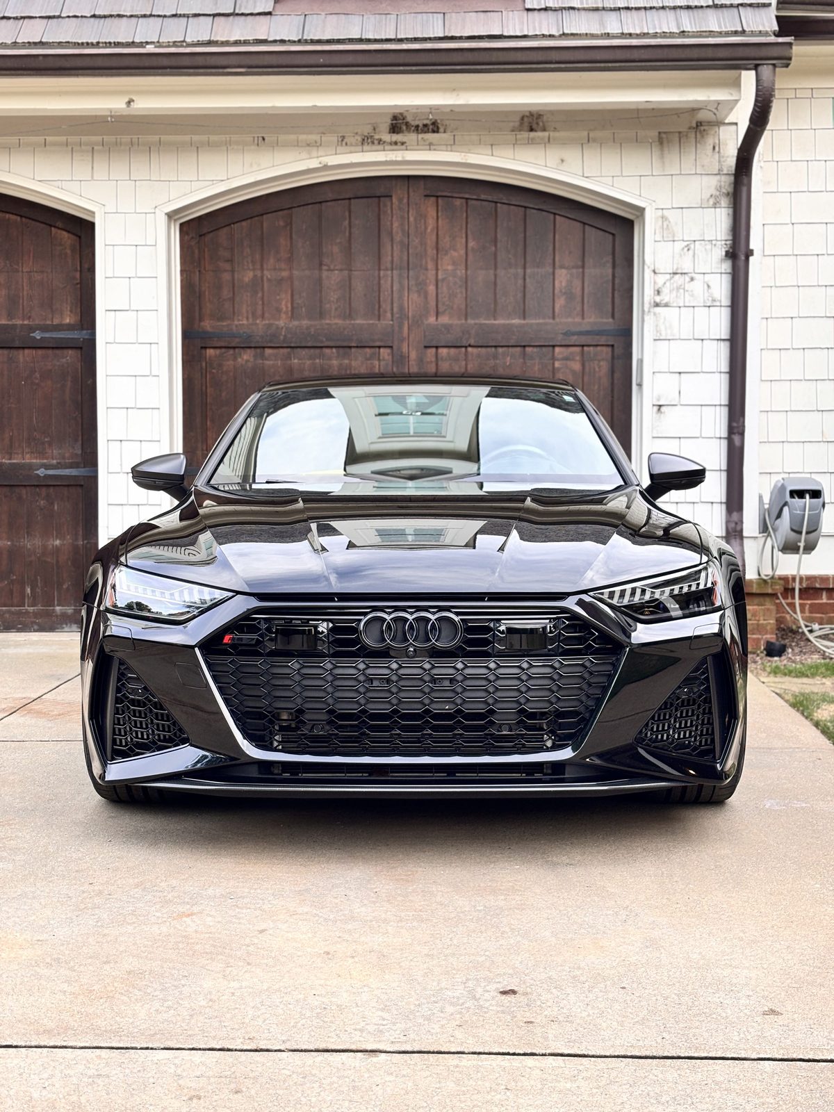 Gloss black car, front view, parked in a driveway