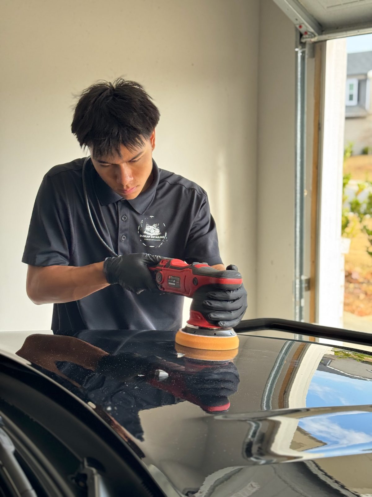 Caleb Dunlap at work, polishing a black car